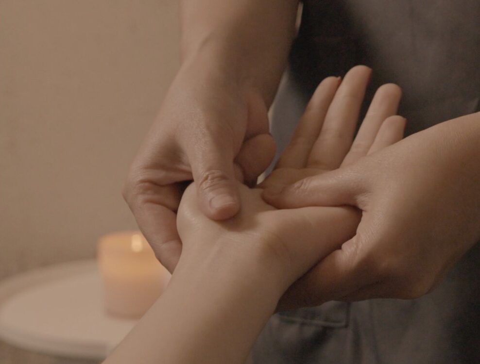 Therapist at Siesta Head Spa in Bangkok providing a relaxing hand massage to a client, enhancing relaxation and well-being.