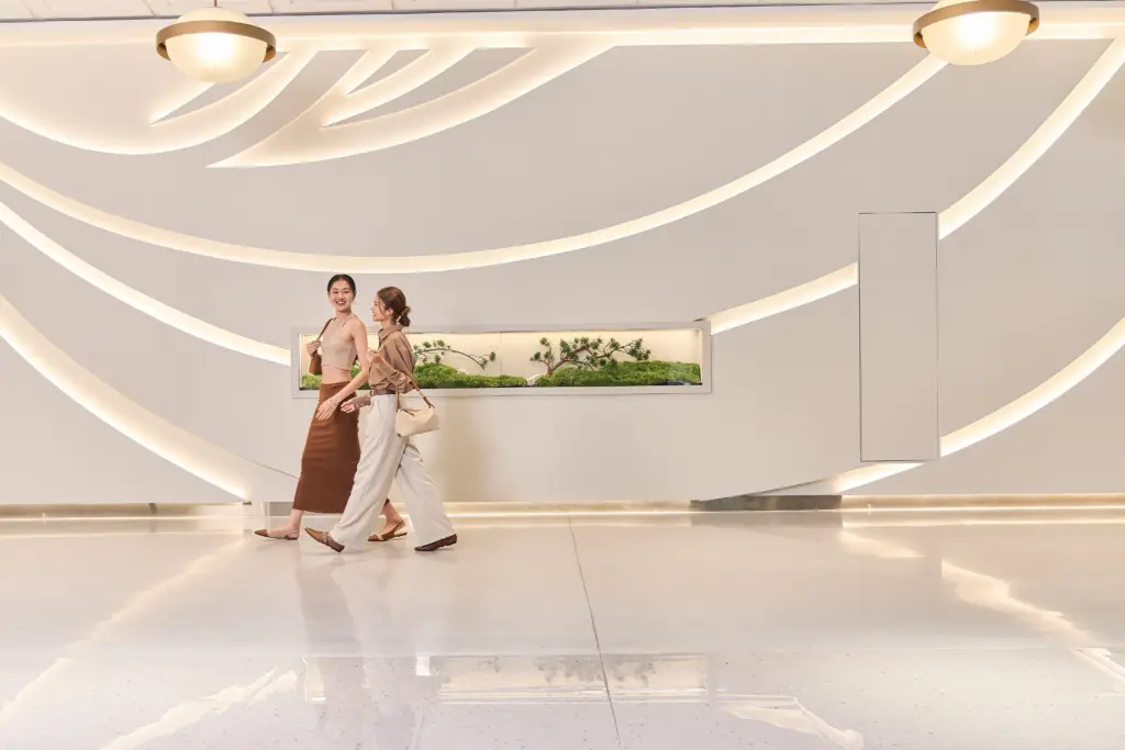 Two women walking inside a modern Sukhumvit lifestyle mall with soft lighting and minimalist design, reflecting the street shopping Sukhumvit experience