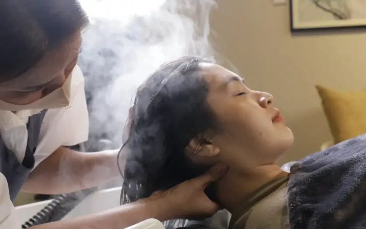 Woman enjoying a relaxing head spa treatment with scalp massage and steam therapy at Siesta Head Spa and Salon in Bangkok