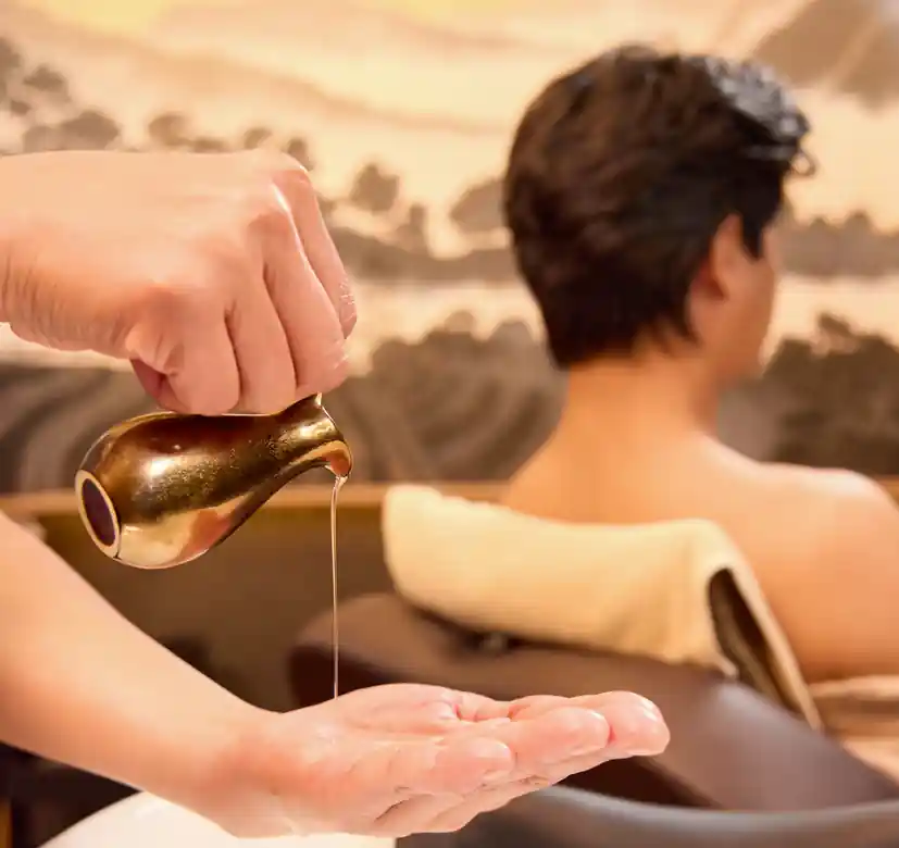 Therapist performing a warm oil head massage during the Aroma Oil Tranquility Program.