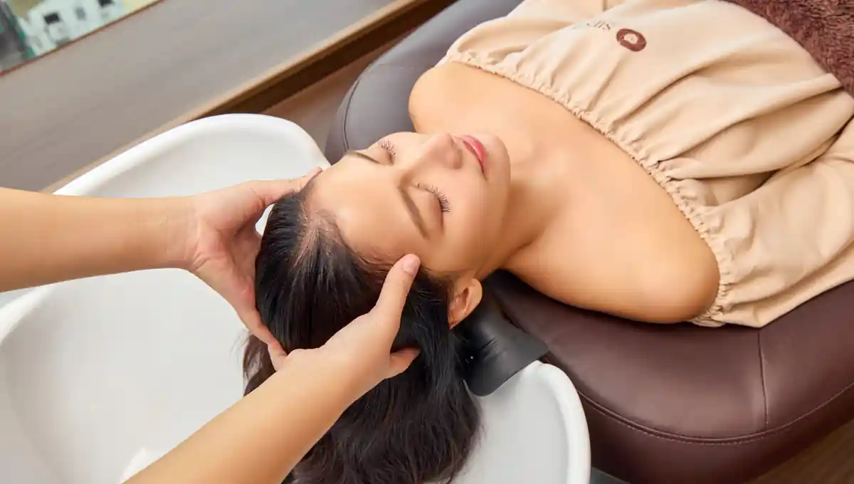 Therapist performing a Signature Thai head massage during the Oway Scalp Solution program.