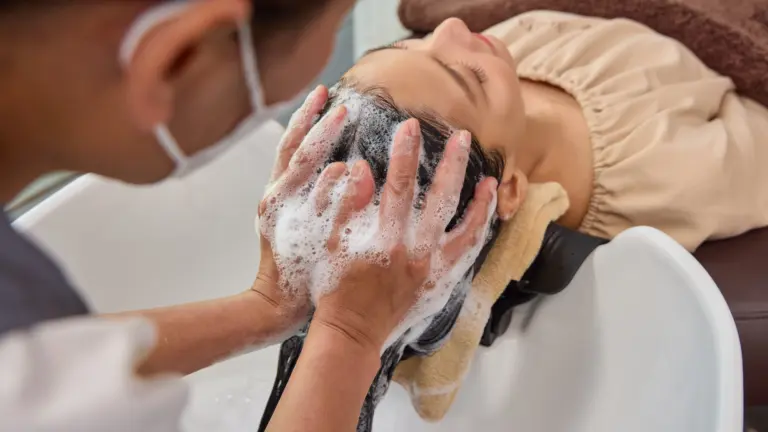 Therapist gently washing and massaging a female client’s scalp during a Head Spa treatment to care for clean, refreshed hair and scalp.