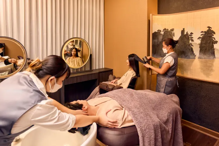 Two guests receiving Head Spa treatments in a private couple room at Siesta EMSPHERE